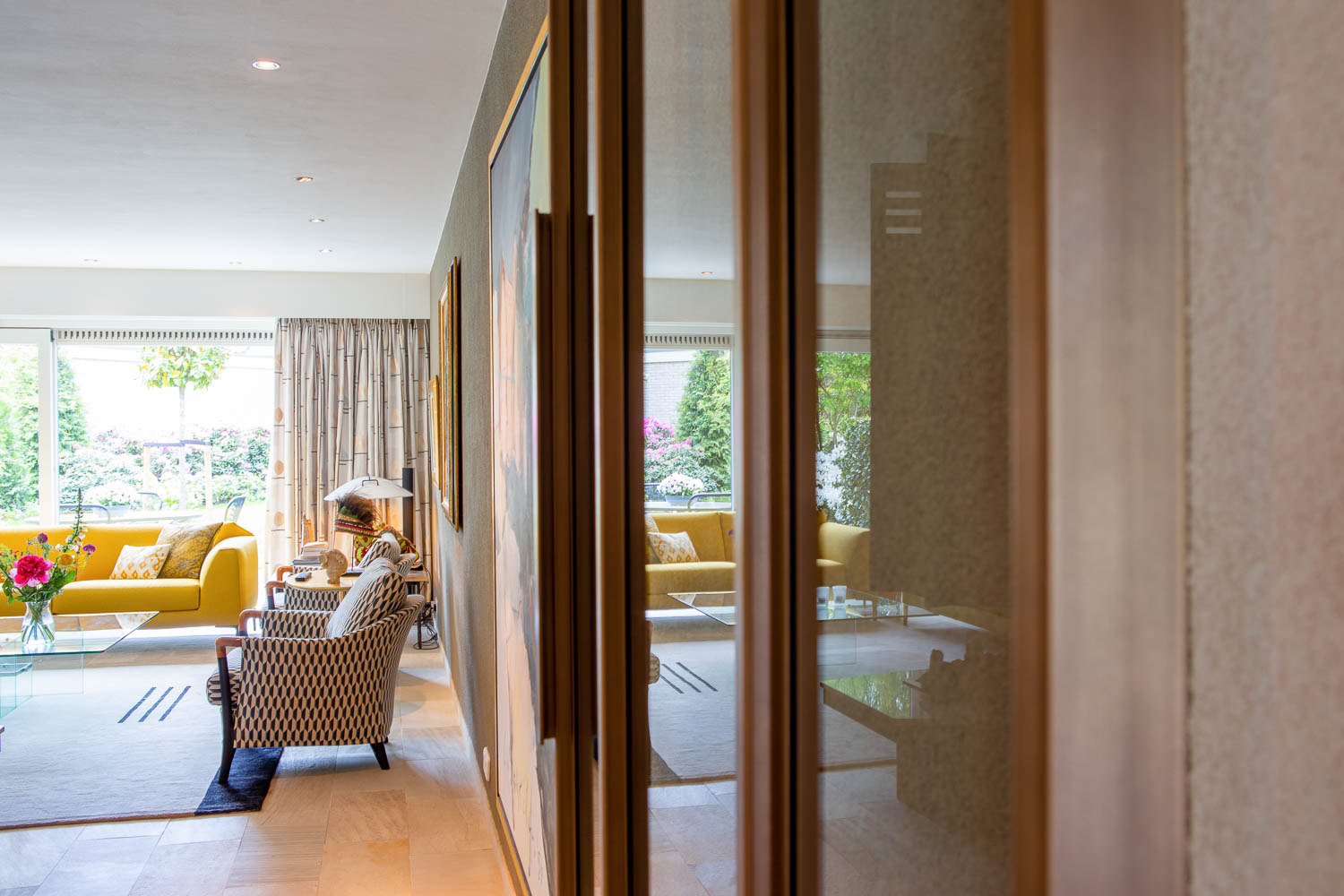 Bronzen stalen taatsdeur met glas in een luxe interieur met kunst en warme tinten.
